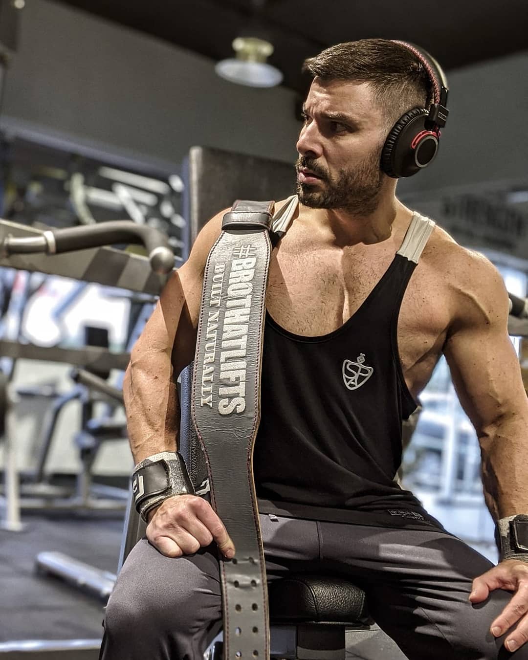 Athlete sitting on a bench with his custom bespoke olympic weightlifting belt over his shoulder