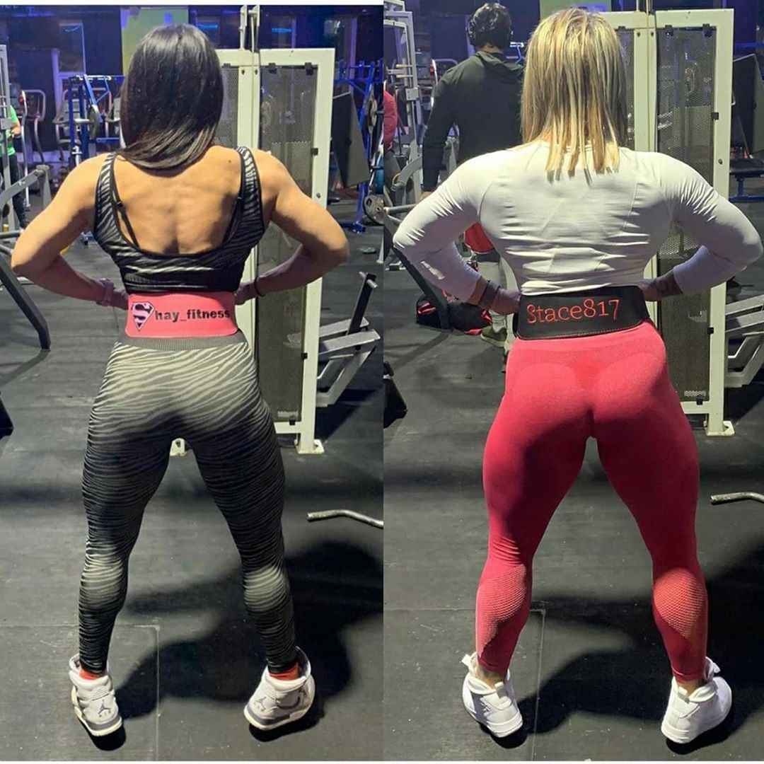 Two woman facing away from the camera posing with their bespoke olympic custom belts