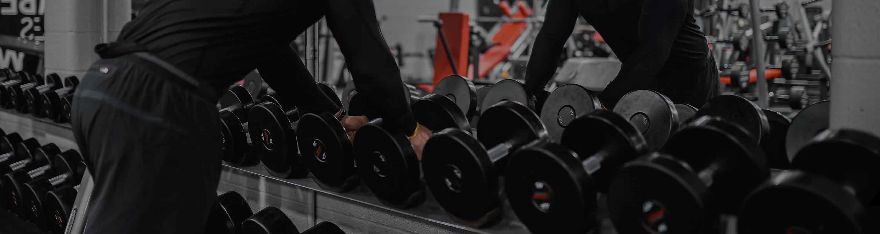 Category banner - person lifting weights of a dumbbell rack.